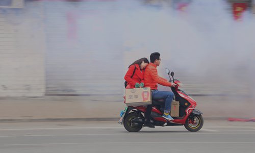 A couple on a motorcycle passes heavy smoke emitted from fireworks on Spring Festival in Hefei, Anhui Province. Photo: IC