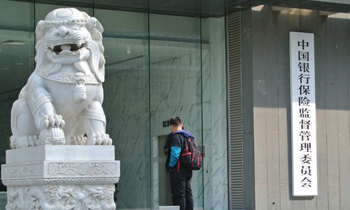 Two people chat outside the headquarters of the China Banking and Insurance Regulatory Commission on April 8. Photo: IC
