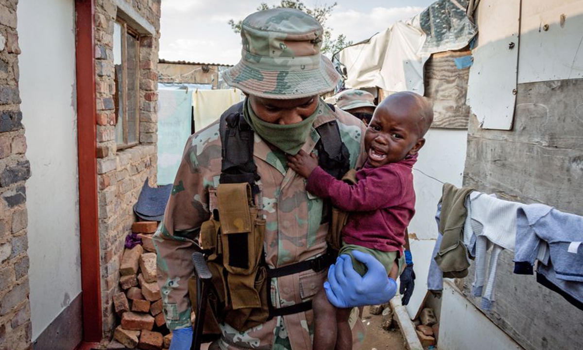 A soldier of South African National Defense Force carries a baby in his arm in Johannesburg, South Africa, April 20, 2020. (Photo by Yeshiel/Xinhua)