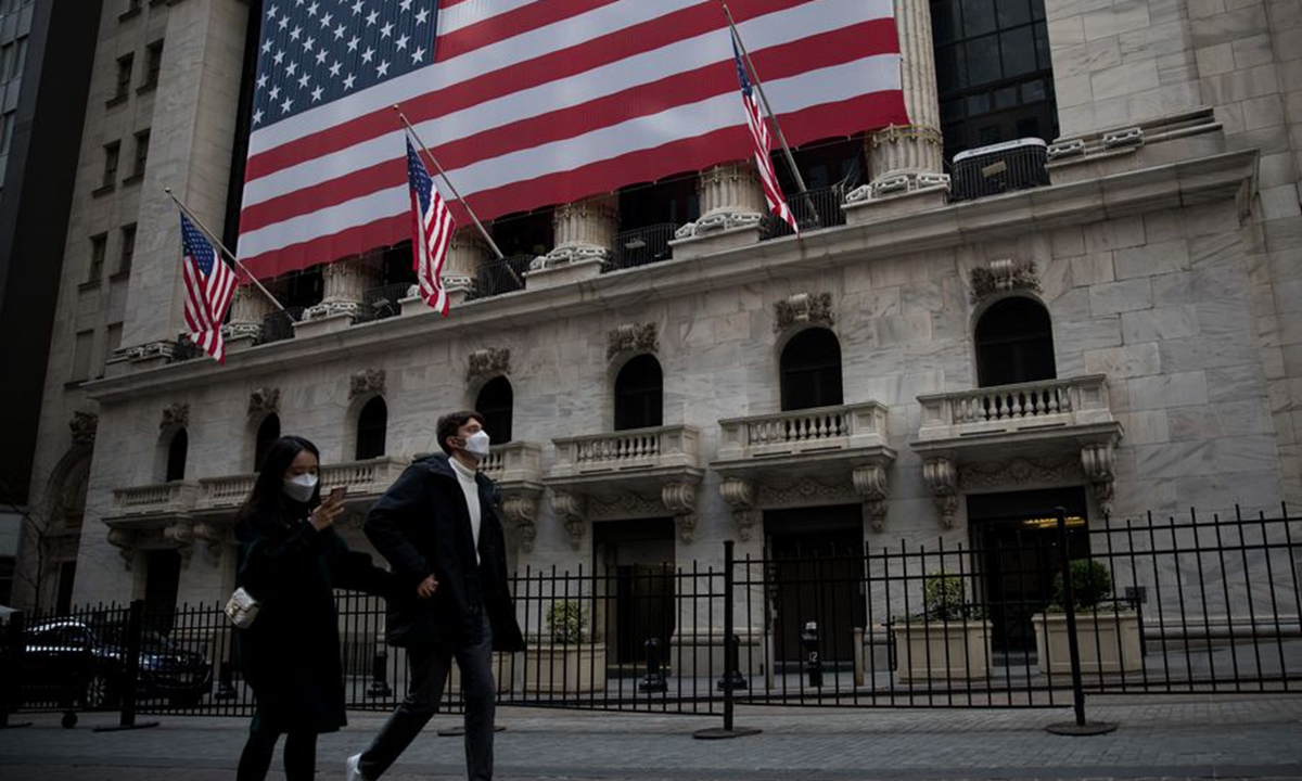Pedestrians wearing face masks walk past the New York Stock Exchange in New York, the US, on March 18. Photo: Xinhua