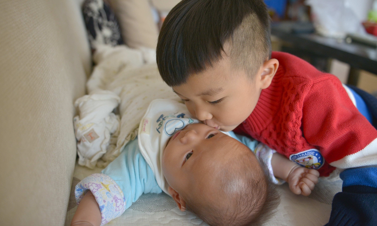 The older brother kisses his younger brother on his face in a family of two children in Guiyang, Southwest China’s Guizhou Province. Photo: VCG