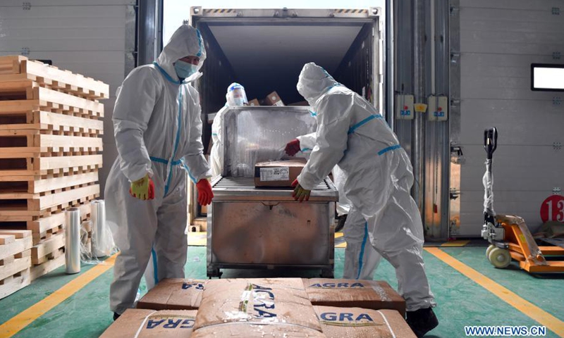 Staff members lie imported food on a disinfection machine at a supervised warehouse for imported cold chain food in Zhengzhou, central China's Henan Province, Jan. 22, 2021. Two supervised warehouses for imported cold chain food have been put into use in Zhengzhou on Jan. 20. All of the imported cold chain food entering Zhengzhou would be tested and disinfected here.Photo:Xinhua