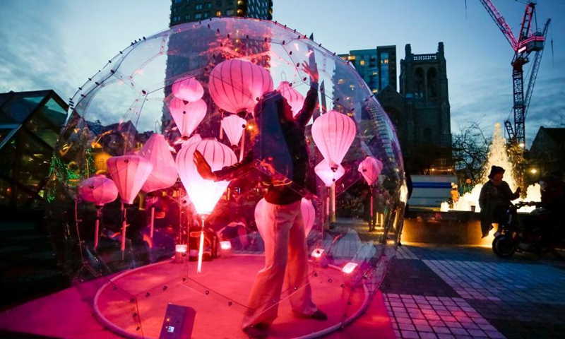 A dancer performs inside a bubble installation during the Dance Bubbles show at Wall Centre Plaza in downtown Vancouver, Canada, March 12, 2021. The show features large brightly-lit bubbles with dancers inside and provides physically distanced entertainment for residents. Photo: Xinhua