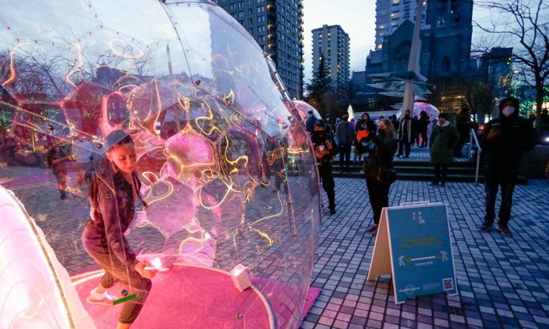 A dancer performs inside a bubble installation during the Dance Bubbles show at Wall Centre Plaza in downtown Vancouver, Canada, March 12, 2021. The show features large brightly-lit bubbles with dancers inside and provides physically distanced entertainment for residents. Photo: Xinhua