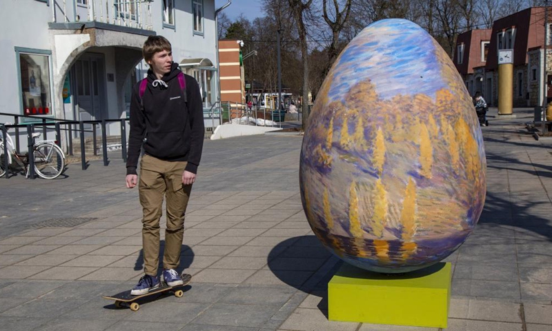 A man looks at an Easter egg decoration in Ogre, Latvia, on March 26, 2021.Photo:Xinhua