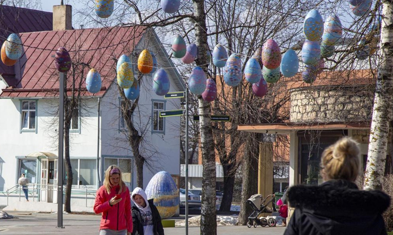 People walk under Easter egg decorations in Ogre, Latvia, on March 26, 2021.Photo:Xinhua