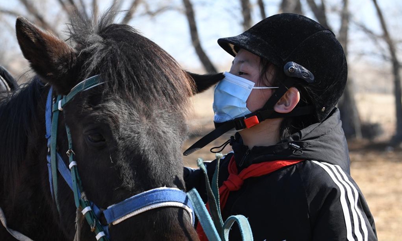 Marmar Berik, a senventh grade student of Oymak Boarding School, kisses a horse during an equestrian class in Burqin County, northwest China's Xinjiang Uygur Autonomous Region, March 30, 2021. People in Xinjiang Uygur Autonomous Region have a tradition of horse breeding and riding. Photo: Xinhua