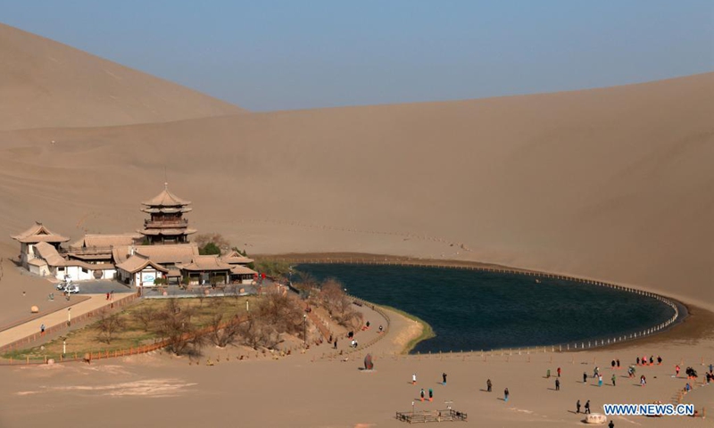 Tourists visit Mingsha Mountain and Yueyaquan (Crescent Spring) scenic spot in Dunhuang City, northwest China's Gansu Province, April 3, 2021. (Photo by Zhang Xiaoliang/Xinhua)