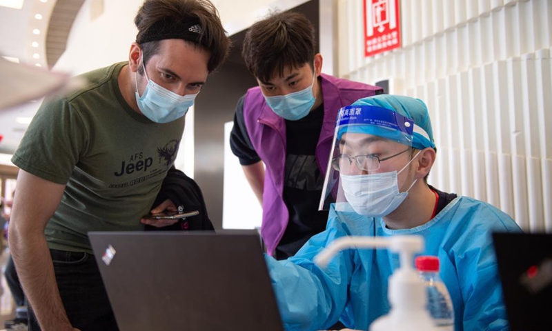 A foreign recipient (L) gets registered for a dose of Sinovac COVID-19 vaccine at a vaccination site in Tsinghua University, Beijing, capital of China, April 3, 2021. Beijing has recently started COVID-19 vaccination for foreign nationals in the city. Foreign nationals aged 18 and above may, following the principle of voluntary participation, giving informed consent and assuming personal responsibility for risk, take the COVID-19 vaccine. (Xinhua)