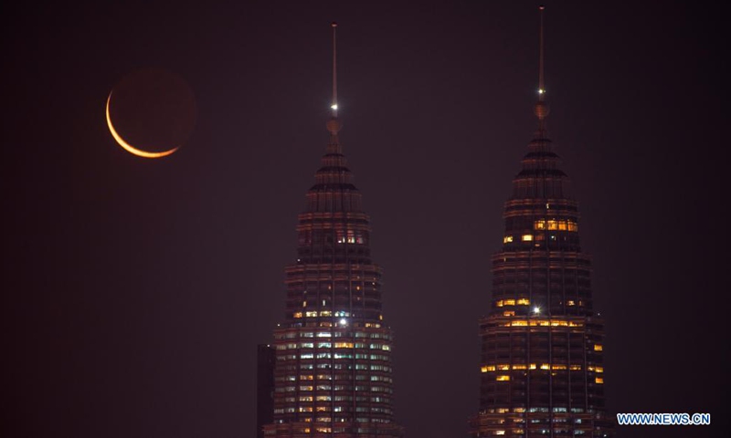 A crescent moon is seen in the sky above the city of Kuala Lumpur, Malaysia, April 10, 2021. (Photo by Chong Voon Chung/Xinhua)