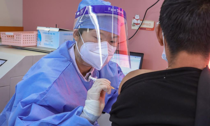 A medical worker injects a man with a dose of COVID-19 vaccine on a mobile vaccination vehicle outside the Donghua Gate of the Palace Museum in Beijing, capital of China, April 13, 2021. The bus-like facilities, equipped with vaccination stations, medical refrigerators and first-aid equipment, have been rolled out in different districts of Beijing to save time and improve inoculation efficiency.(Photo: Xinhua)