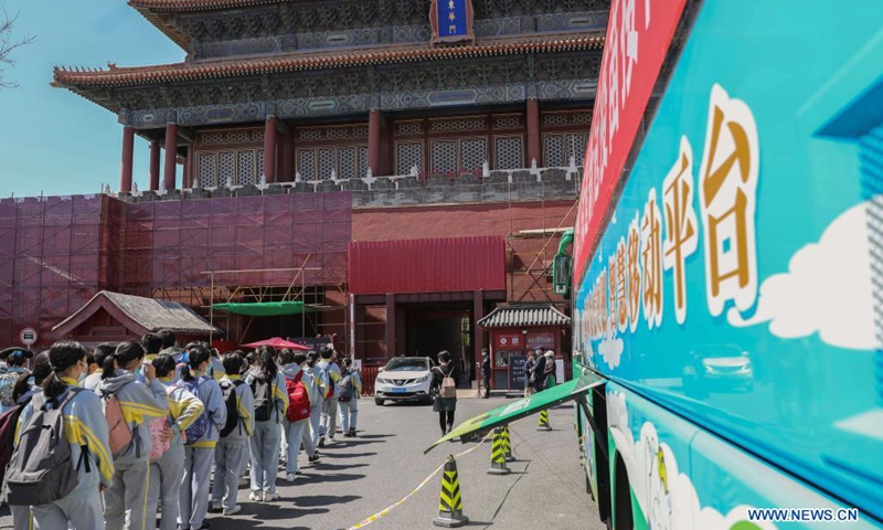 Tourists walk past a mobile COVID-19 vaccination vehicle outside the Donghua Gate of the Palace Museum in Beijing, capital of China, April 13, 2021. The bus-like facilities, equipped with vaccination stations, medical refrigerators and first-aid equipment, have been rolled out in different districts of Beijing to save time and improve inoculation efficiency.(Photo: Xinhua)