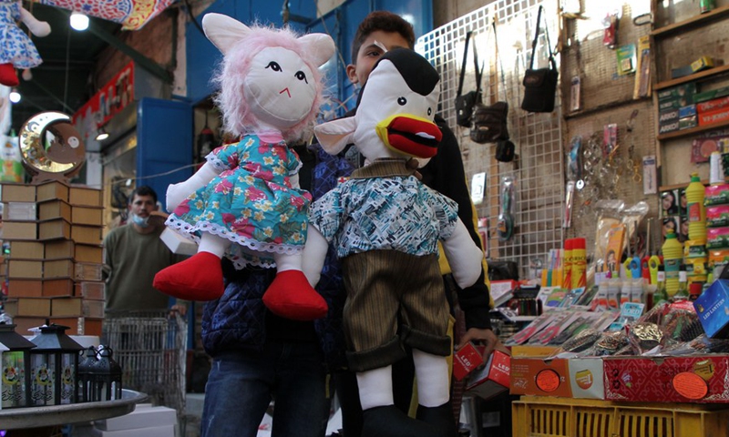 Photo taken on April 12 shows Palestinian children hold toys at al-Zawiya market.(Photo: Xinhua)