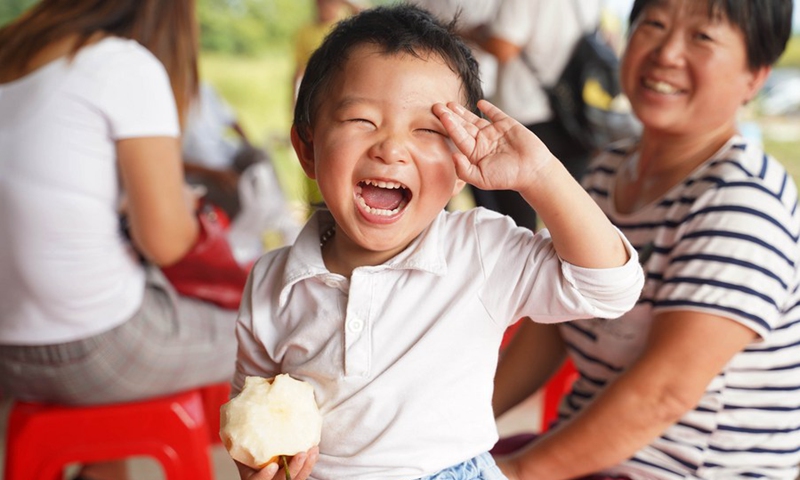 A smiling child eats pear at a pear planting base at Xiaogang Village in Fengyang County, east China's Anhui Province, on Sept. 15, 2018.(Photo: Xinhua)