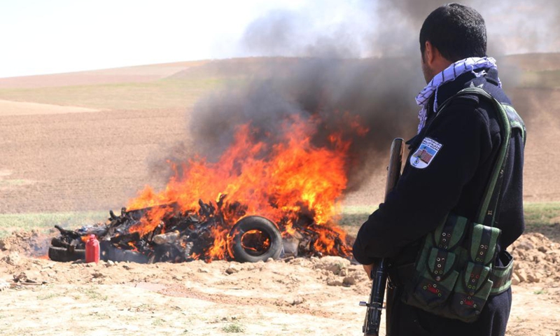 An Afghan policeman stands guard as smoke rises from burning drugs in Sari Pul province, April 17,2021. The Afghan authorities burned about one ton of seized narcotic drugs in Sari Pul province, Afghanistan, a local official said on Saturday. (Photo: Xinhua)