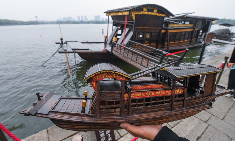Han Minghua stands beside the Red Boat with a self-made Red Boat model in hand on the bank of the Nanhu Lake in Jiaxing City, east China's Zhejiang Province, April 13, 2021.(Photo: Xinhua)
