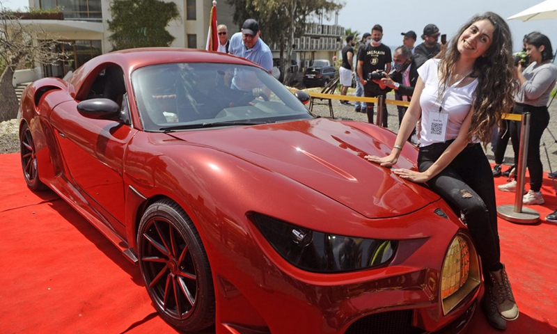 A woman poses for photos with the first locally made electric car at the launch ceremony in Beirut, Lebanon, on April 24, 2021.(Photo: Xinhua)
