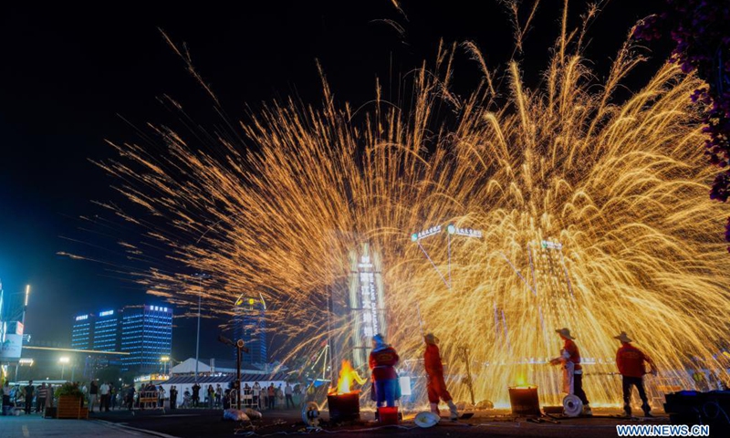Staff members perform iron flowers, a folk art performance of throwing molten iron to create fireworks, at a block featuring food stalls in Wenzhou, east China's Zhejiang Province, April 30, 2021.Photo:Xinhua