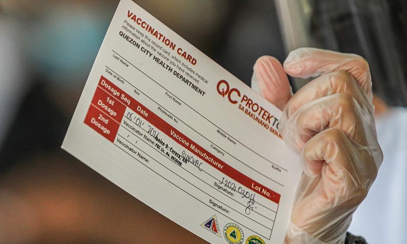 A health worker shows a vaccination card before giving a dose of the Sinovac COVID-19 vaccine to resident in Manila, the Philippines on May 1, 2021.Photo:Xinhua