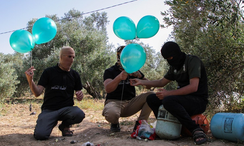 Masked Palestinian protesters prepare incendiary balloons before releasing them by wind into southern Israel, as a protest against the violence in the Old City of Jerusalem, on May 8, 2021.(Photo: Xinhua)