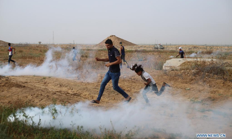 Palestinians run to take cover from tear gas canisters fired by Israeli troops during a protest against the violence in Jerusalem, on the Gaza-Israel border east of southern Gaza Strip city of Khan Younis, on May 9, 2021. About 290 Palestinians were injured over the weekend in clashes with Israel's police at the Al-Aqsa Mosque compound and other parts of East Jerusalem. (Photo: Xinhua)