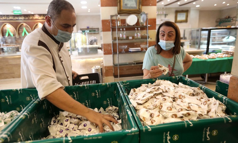 A Ma'amoul maker and a customer are seen at a sweet shop in Beirut, Lebanon, on May 9, 2021.(Photo: Xinhua)