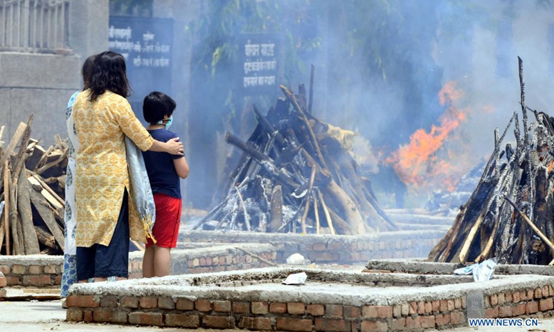 Family members look at the funeral pyres for a COVID-19 victim at Sarai Kale Khan crematorium in New Delhi, India, May 12, 2021.(Photo: Xinhua)