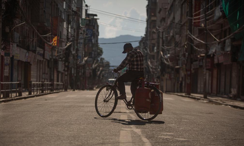 A man rides a bicycle carrying gas cylinder on the street during the lockdown imposed to curb the COVID-19 infections in Kathmandu, Nepal, May 14, 2021.Photo:Xinhua