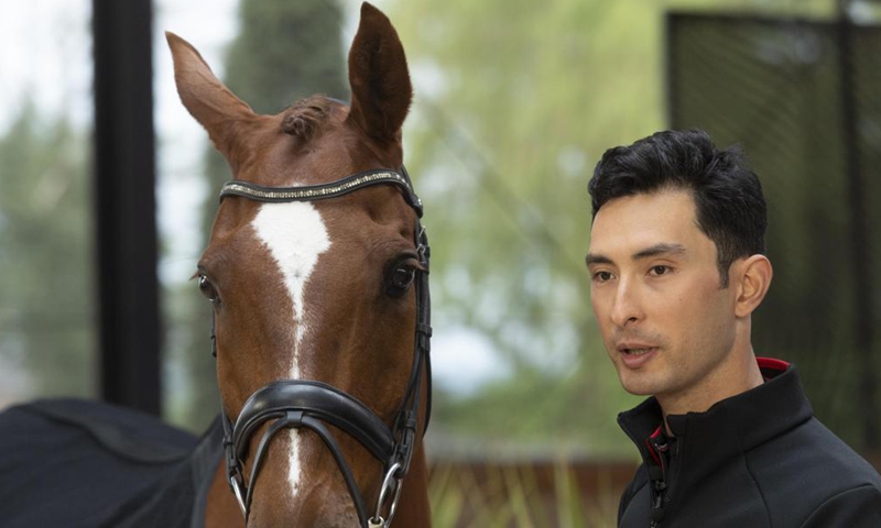 Alex Hua Tian stands next to his horse Don during a press conference in Cheshire, Britain, on May 14, 2021. China's first Olympic rider Alex Hua Tian unveiled his new 'Hoof Print to Tokyo' slogan for the Olympic Games at the press conference at Pinfold Stables in Cheshire, Britain.Photo:Xinhua