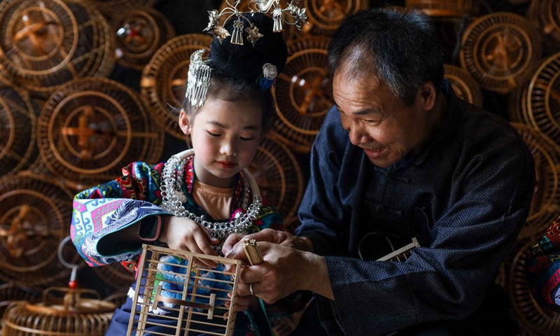 Intangible cultural heritage inheritor Yang Xueliang (R) instructs a girl of the Miao ethnic group in making birdcage at Wanda Town of Danzhai County in Qiandongnan Miao and Dong Autonomous Prefecture, southwest China's Guizhou Province, May 15, 2021.(Photo: Xinhua)