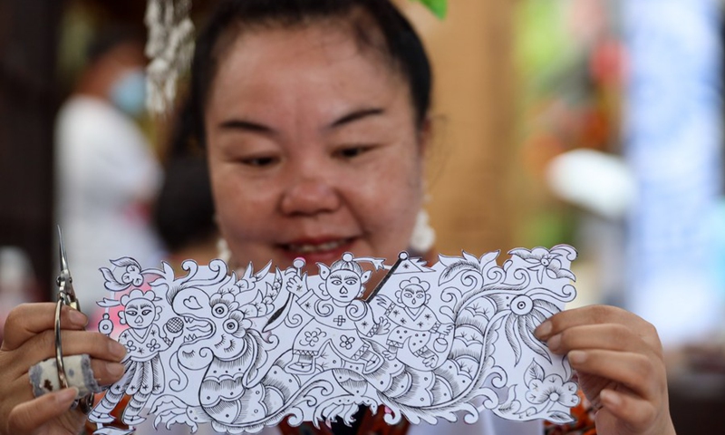 Intangible cultural heritage inheritor Jiang Wenying shows a piece of paper cutting work of the Miao ethnic group at Wanda Town of Danzhai County in Qiandongnan Miao and Dong Autonomous Prefecture, southwest China's Guizhou Province, May 15, 2021.(Photo: Xinhua)