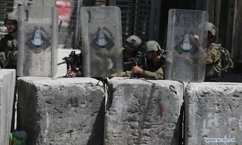 Israeli soldiers aim their weapons at protesters during a protest against the continued Israeli airstrikes on the Gaza Strip, in the West Bank city of Hebron, on May 18, 2021.(Photo:Xinhua)
