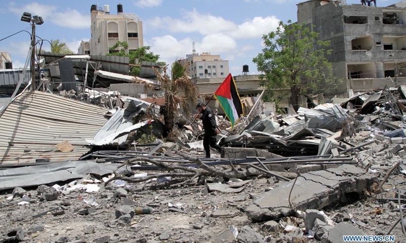 A Palestinian policeman of the Hamas government holds a Palestinian flag and inspects the damage of a governmental building attacked by Israeli airstrikes in Gaza city, on May 22, 2021.Photo:Xinhua