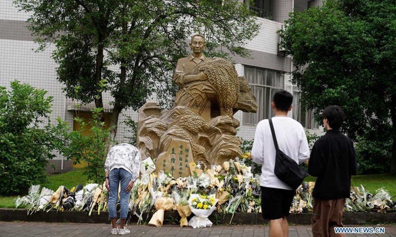 Students present flowers in front of a statue of Yuan Longping in Southwest University in southwest China's Chongqing, May 22, 2021. Chinese scientist Yuan Longping, renowned for developing the first hybrid rice strain that relieved countless people of hunger, died of organ failure at 91 on Saturday. Yuan graduated from the Southwest Agricultural College (now the Southwest University) in 1953.Photo:Xinhua