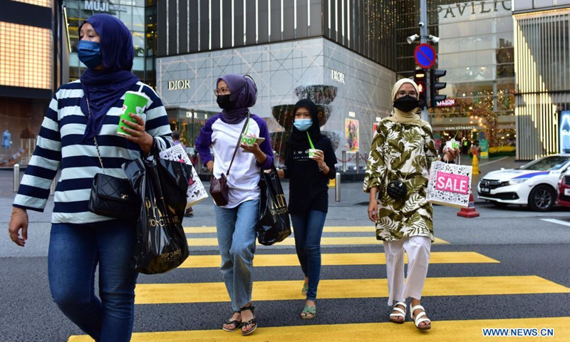 People wearing face masks walk across a street in Kuala Lumpur, Malaysia, May 22, 2021. Malaysia announced further tightening restrictions on Saturday under its nationwide movement control order (MCO) as the country's accumulative COVID-19 cases topped 500,000.(Photo: Xinhua)
