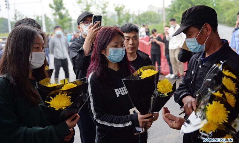 A staff member (R) receives flowers presented by local people for Yuan Longping at the Mingyangshan funeral parlor in Changsha, central China's Hunan Province, May 22, 2021. The hearse carrying Yuan Longping's body left the Xiangya Hospital of Central South University for funeral parlor in Changsha on Saturday. Halfway through, the hearse made a detour at the Hunan Hybrid Rice Research Center where Yuan lived and worked for a long time.(Photo: Xinhua)