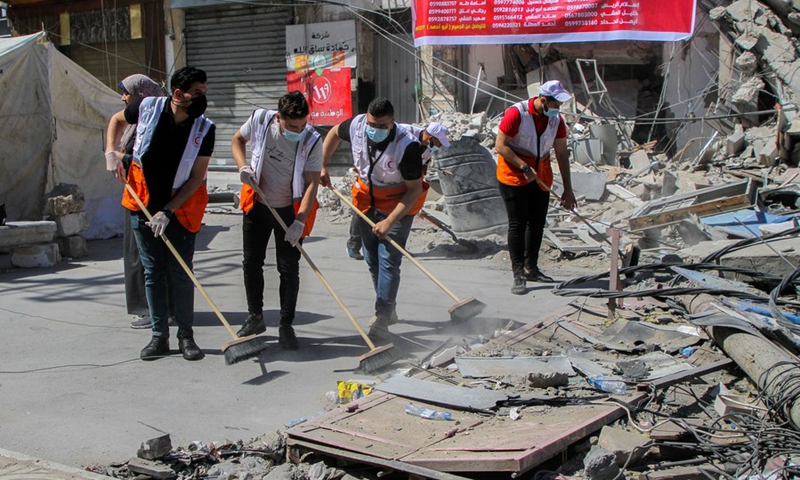 Under a youth initiative, young Palestinian volunteers clean a street of the debris left by Israeli airstrikes, in Gaza City, on May 23, 2021.(Photo: Xinhua)