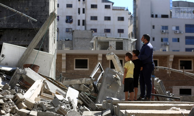 Palestinians stand on the rubble of their houses destroyed during an Israeli air strike in Gaza City, May 23, 2021.(Photo: Xinhua)