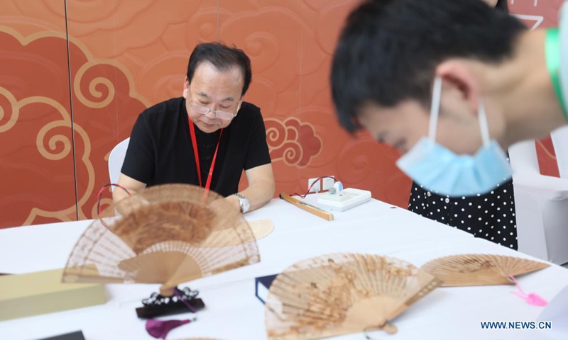 An intangible cultural heritage inheritor shows the skills of making sandal fans at an exhibition held on the occasion of China's Cultural and Natural Heritage Day in Shanghai, east China, June 12, 2021. An exhibition of Chinese traditional handicrafts was held on Saturday, this year's Cultural and Natural Heritage Day. Since 2006, China has celebrated cultural heritage day on the second Saturday of June. In 2017, it was renamed Cultural and Natural Heritage Day. (Xinhua/Wang Xiang)
