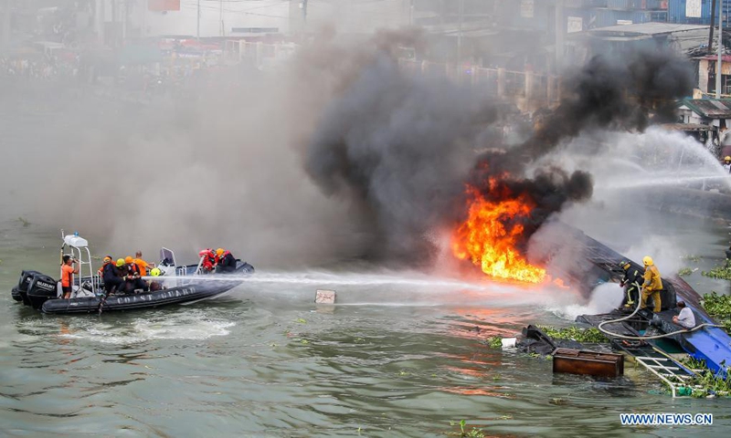 Firefighters and members of the Philippine Coast Guard try to put out a fire engulfing a cargo ship at a wharf in Manila, the Philippines on June 12, 2021. Six crew members were injured and two others unaccounted for when a small cargo ship caught fire while refueling here at a wharf on Saturday morning, the Philippine Coast Guard (PCG) said. (Xinhua/Rouelle Umali)