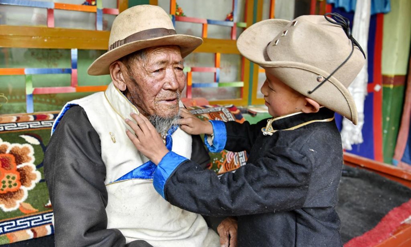 Sonam's grandson helps him turn up the collar at home in the county of Xaitongmoin, Xigaze City, southwest China's Tibet Autonomous Region, April 16, 2021. Sonam, 80, led an arduous life before the democratic reform in Tibet in 1959. When he was born, his father passed away because of overwork. Photo:Xinhua