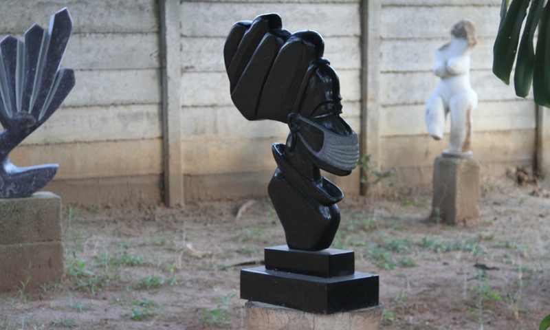 A stone sculpture depicting a woman wearing a face mask is seen at David Ngwerume's art gallery in Greendale, Harare, Zimbabwe, on April 26, 2021.(Photo: Xinhua)