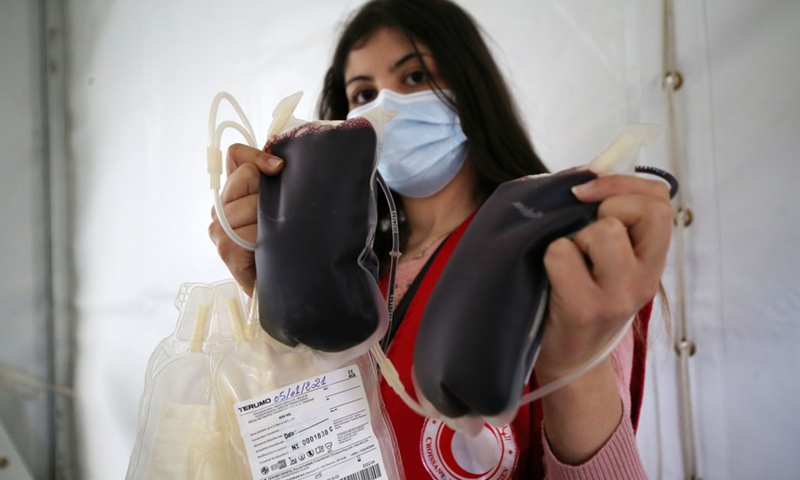 A medical worker from the Algerian Red Crescent Society shows blood collected from donors at a blood donation point in downtown Algiers, Algeria, Jan. 5, 2021.(Photo: Xinhua)
