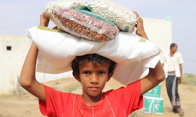 Photo taken on Feb. 14, 2021 shows a boy carrying the food donated by a charity group in Hajjah Province, north Yemen. (Photo: Xinhua)