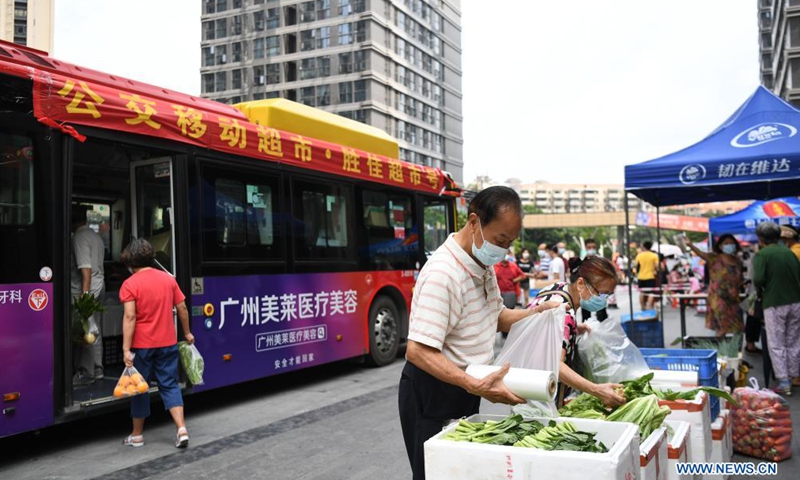 Residents shop at a bus-based mobile market in Liwan District of Guangzhou, south China's Guangdong Province, June 19, 2021. Guangzhou has recently launched a bus-based mobile shopping service, which sends food and daily necessities to the city's risk areas by bus, making it easier for the citizens under epidemic control to shop at their residential areas.Photo:Xinhua