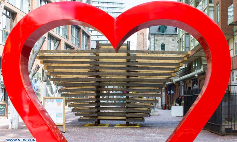 An art installation is seen through a red heart sculpture during the exhibition of the 2021 Winter Stations international design competition in Toronto, Canada, on June 22, 2021.(Photo: Xinhua)