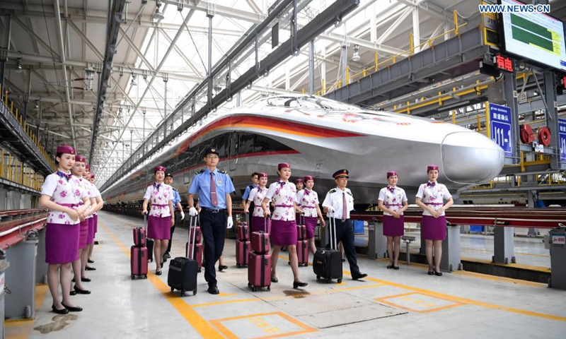 Crew members pose for photos with a CR400AF Fuxing intelligent bullet train in southwest China's Chongqing, June 23, 2021. The CR400AF Fuxing intelligent bullet train will be put into service on the railway linking Chengdu, capital city of southwest China's Sichuang Province, and Chongqing on Friday.(Photo: Xinhua)