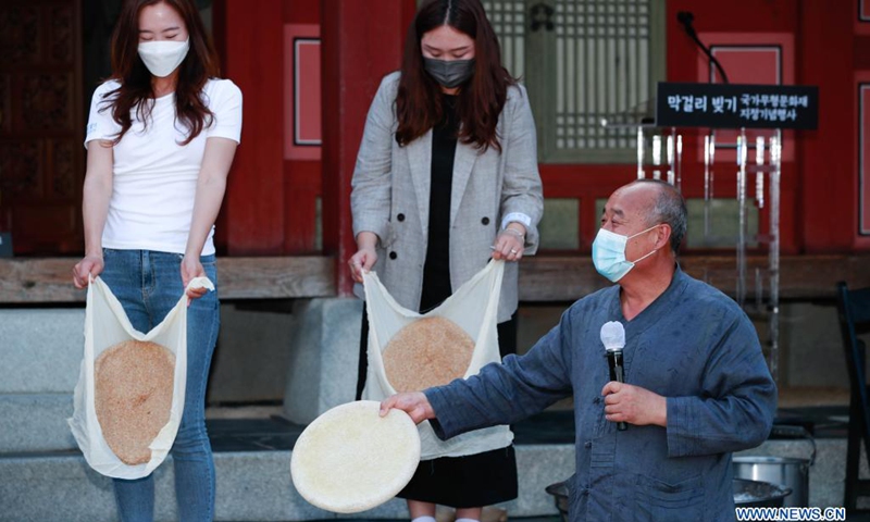 Guests experience processing nuruk, a fermentation starter used in making makgeolli, at Hwaseong Haenggung Palace in Suwon, South Korea, June 26, 2021. Makgeolli, a traditional Korean alcoholic beverage made from rice, has been listed as South Korea's national intangible cultural heritage recently.(Photo: Xinhua)
