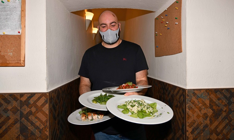 Simone Dordei, co-owner of Osteria La Gensola restaurant, serves dishes to customers in Rome, Italy, on June 24, 2021. (Photo: Xinhua)
