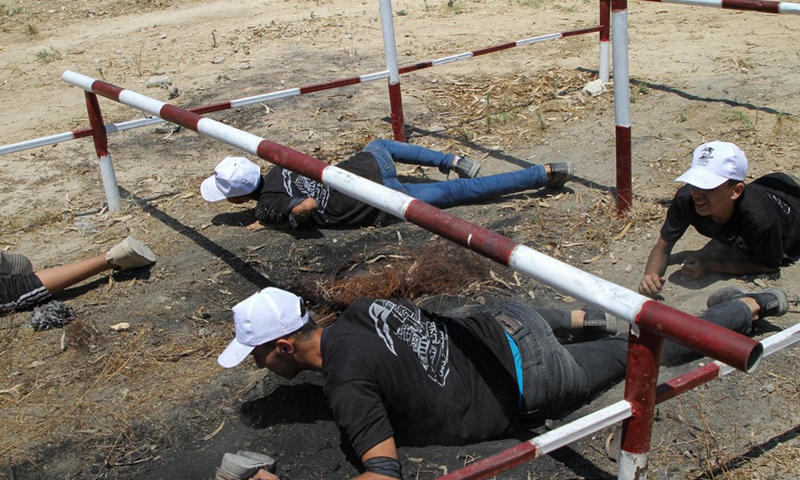 Palestinian teenage boys crawl under bars at a military summer camp run by Hamas at the Al-Yarmouk military site, east of Gaza City, on June 26, 2021.(Photo: Xinhua)